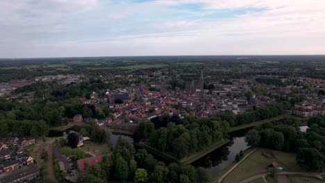 Approach-and-aerial-rotating-pan-around-historic-Dutch-city-center-of-Groenlo-with-church-tower-rising-above-the-authentic-medieval-rooftops