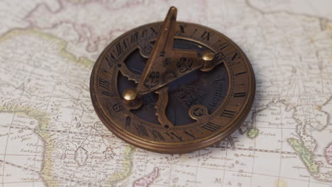 An-atique-brass-sundial-navigational-instrument-on-a-vintage-world-map