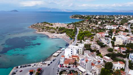 Aerial-drone-view-to-the-beautiful-beach-of-Moni-island,-next-to-the-village-Perdika-on-Aegina-island-with-turquoise-sea,-Saronic-Gulf,-Greece
