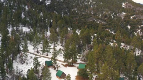 Cabins-in-the-snowy-pine-forest-of-the-Tehachapi-mountains-in-winter---aerial-view