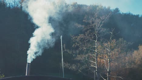 White-smoke-billows-from-the-chimney-of-house-in-countryside