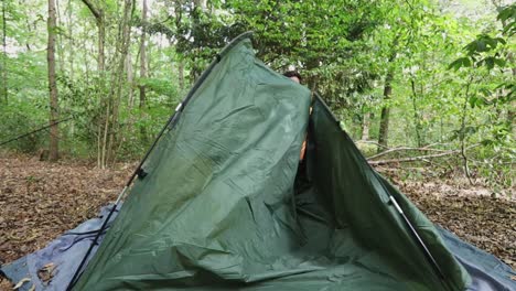 Person-starts-to-build-tent-in-forest-landscape,-lonely-traveler-in-slow-motion
