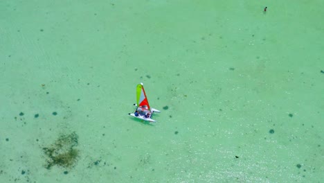 Aerial-view-around-a-small-catamaran-in-shallow,-turquoise-sea,-in-Dominican-republic---circling,-drone-shot