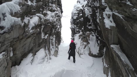 Static-shot-of-a-girl-walking-on-ice-and-snow-in-a-big-cave-in-Björkliden,-Sweden