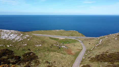 Sunny-Great-Orme-mountain-sea-view-North-Wales-aerial-coastal-island-moorland-landscape-low-dolly-left-fast