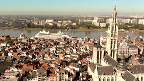 Antwerp-Cathedral-view-over-Cruise-ship-anchored-on-Scheldt-river,-Belgium---Aerial-wide-panoramic-shot