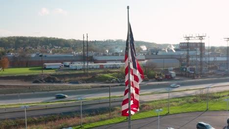 American-flag-in-USA-highlights-manufacturing-plant,-busy-highway-infrastructure,-electric-and-energy-generation-and-consumption-theme-in-America