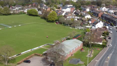 Aerial-drone-shot-panning-over-village-football-pitch-and-housing-estate,-England