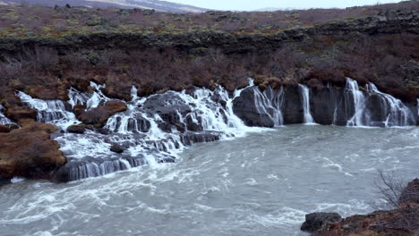 Toma-Estática-De-Cascadas-De-Hraunfossar-Y-Arroyo-Que-Fluye-Con-Hermoso-Paisaje-De-Islandia