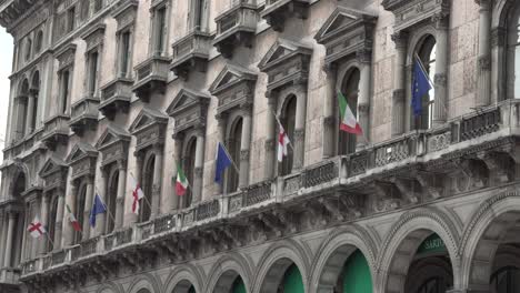Muchas-Banderas-Italianas,-Europeas-Y-De-Milán-En-El-Viento-En-El-Antiguo-Palacio-En-El-Centro-De-Milán