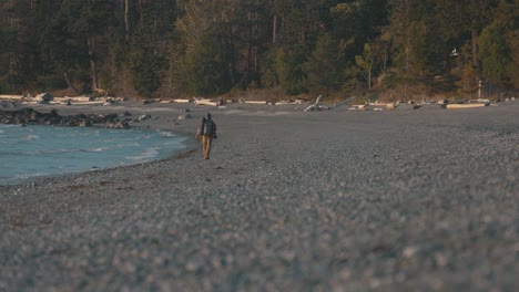 Hiker-walks-in-a-rocky-beach-in-the-pacific-coast-of-Sunshine-Coast,-British-Columbia,-Canada