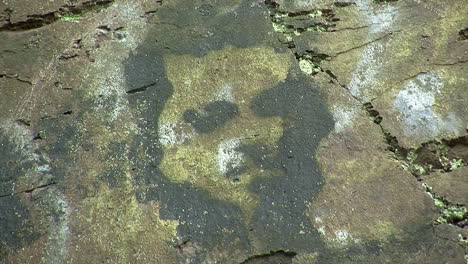 Stenciled-graffiti-of-a-man's-face-on-a-rock-surface