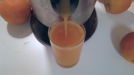 Orange-juice-pouring-in-glass-on-white-table