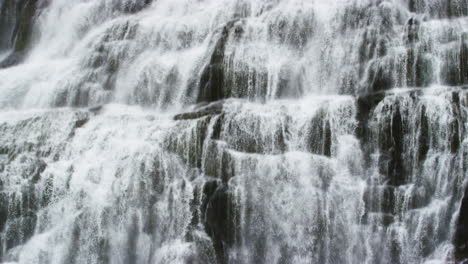 Powerful-waterfall-stream-falling-down-mountain-in-close-up-tilting-down-view