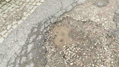 Cracked-Asphalt-Road-With-Pothole-And-Puddle