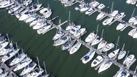 Flying-above-luxury-yachts-and-sailboats-reflections-on-sunny-Conwy-marina-birdseye-aerial-slow-right-dolly-view