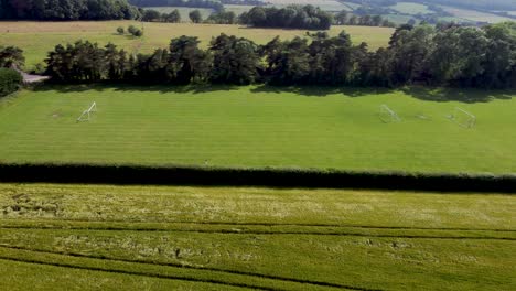 Flying-alongside-a-green-village-football-pitch-in-Kent,-UK