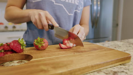 Woman-cutting-up-a-fresh-strawberries-on-cutting-board