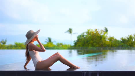 Beautiful-Woman-Sits-in-Shallow-Swimming-Pool-Water,-Tropical-Holiday