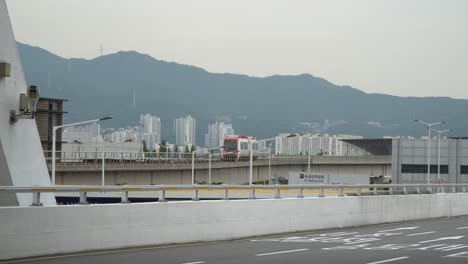 Tren-En-El-Ferrocarril-Al-Aeropuerto-Internacional-De-Gimhae-En-Busan,-Corea-Del-Sur-Con-Carretera-Asfaltada-En-Primer-Plano