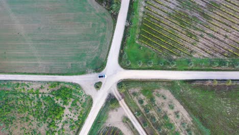 aerial-view-of-a-car-moving-on-empty-road-in-autumn-fields-in-Tuscany,-Italy
