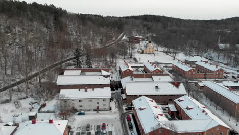 Panning-aerial-shot-of-snow-covering-ground-and-buildings-in-tiny-Swedish-town