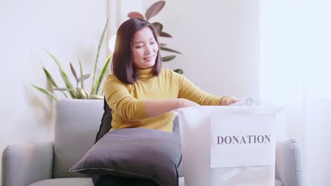 Young-Asian-woman-selecting-clothes-for-donation-and-making-reservations-for-delivery-and-pay-by-credit-card-online