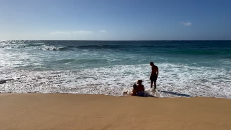 Family-watching-waves-on-a-beach-in-Hawaii