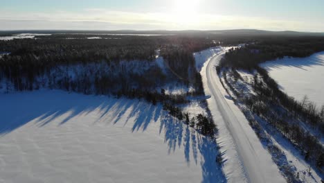 Beautiful-Scenery-Of-Frozen-Road-Between-a-Lush-Forest-In-Lapland-Finland-In-Winter---aerial-shot