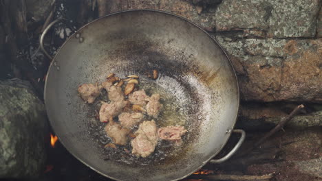 Traditional-Asian-cuisine,-chef-frying-meat-in-stone-stove-in-wok