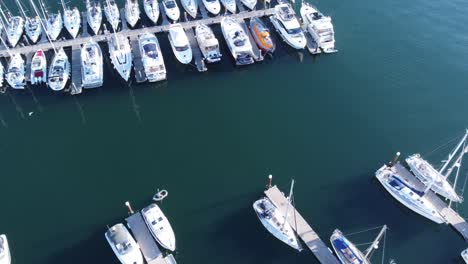 A-forward-flying-drone-shot-of-a-marina-and-lots-of-boats,-that-slowly-tilts-up,-revealing-a-beautiful-harbour-in-the-evening-sun