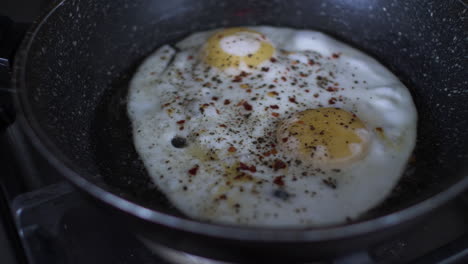 Fried-Eggs-Sprinkled-With-Pepper-And-Chilli-Flakes-Sizzling-In-Frying-Pan