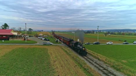 An-Aerial-View-of-an-Antique-Restored-Steam-Train-and-Passenger-Coaches-Approaching-With-Smoke-and-Steam-With-Tourists-and-Spectators-Watching-as-Seen-by-a-Drone