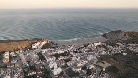 Panning-aerial-shot-facing-directly-at-the-Atlantic-Ocean-from-a-secluded-fishing-village-Burgau-Portugal