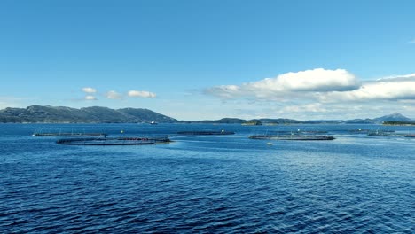 Sailing-close-to-Norwegian-fish-farm-at-Lerøy-Norway---Viewing-rings-in-the-sea-surface-from-a-ship-passing-along-the-location-on-a-sunny-day