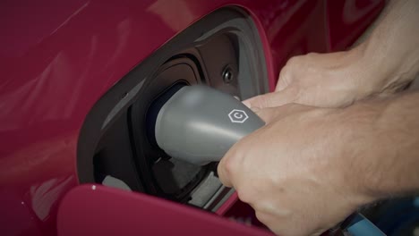 Close-Up-Of-Hands-Inserting-Grey-Charger-Plug-Of-Electric-Hybrid-Car-Into-Connector