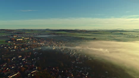 Drone-flying-over-a-village-of-typical-German-architecture-in-low-cloud-covered-countryside