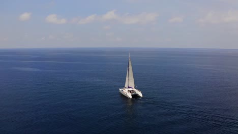 Sailboat-at-sea,-areal-video-over-water-surface-and-boat-floating-on-it