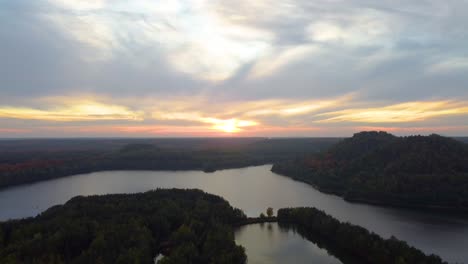 Majestic-lake-water-with-autumn-color-forest-during-sunset,-aerial-view