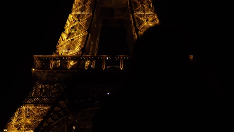 Silhouette-Einer-Frau,-Die-Nachts-Den-Beleuchteten-Eiffelturm-In-Paris,-Frankreich,-Betrachtet