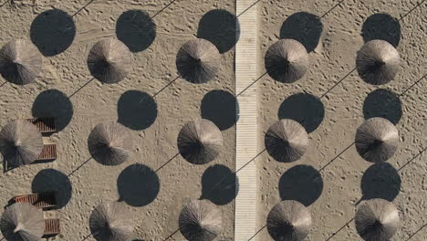 Woven-beach-parasols-and-boardwalk-on-hot-sand-form-repeating-pattern
