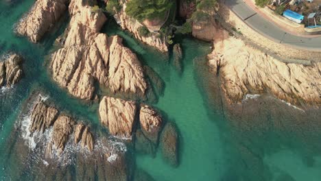 Aerial-view-of-rocks-in-the-transparent-turquoise-blue-Mediterranean-Sea-Sant-Pol-beach-in-S'Agar?
