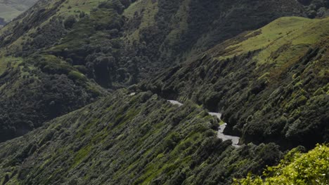 Car-driving-up-a-winding-mountain-road-in-the-coastal-countryside-of-New-Zealand's-north-Island