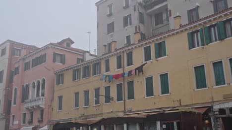 Zeitlupe-Auf-Einem-Gelben-Gebäude-Mit-Kleidern,-Die-Im-Nebel-Eines-Nassen-Tages-In-Venedig-Italien-Zum-Trocknen-Aufhängen