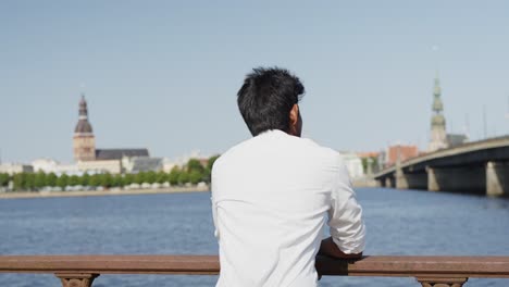 Young-handsome-Indian-boy-relaxed-watching-a-river-in-a-European-city