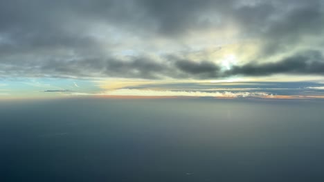 Aerial-view-from-a-jet-cockpit,-pilot-point-of-view,-flying-bellow-some-clouds-and-over-Atlantic-Ocean-near-poruguese-coast