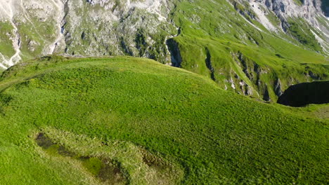 aerial-landscape-slow-motion-of-lush-green-grassy-meadow-in-the-Dolomites-mountain-range-on-a-summer-day