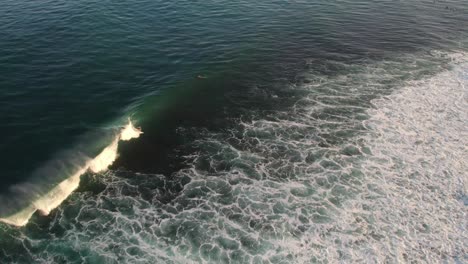 Aerial-view-of-professional-surfer-performing-acrobatic-tricks-in-ocean-water-bali-island-Uluwatu