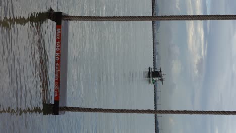 Vertical-video---Boat-and-sea-view-during-high-tide-with-a-beach-seesaw-on-the-water
