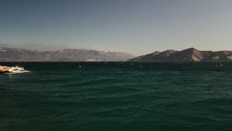 Plain-straight-shot-over-adriatic-sea-with-drone-in-a-coast-of-Baska-in-Croatia-beautiful-colors-blue-sky-big-mountains